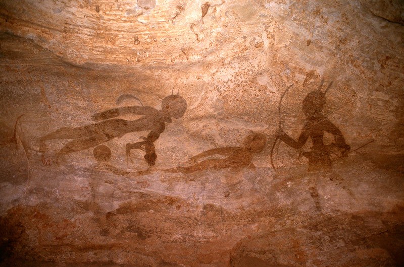 Djanet, Algeria. Right-hand section of painted panel. At right, man moving left with two feathers on head,holds double-curved bow in one hand and arrow in other hand. Image ID: algdja0010034