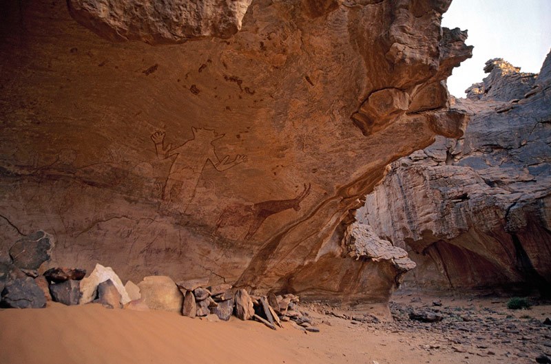 Djanet, Algeria. Painting of mythical figure and antelope. Other faded paintings of people and antelope visible. Image ID: algdja0020005