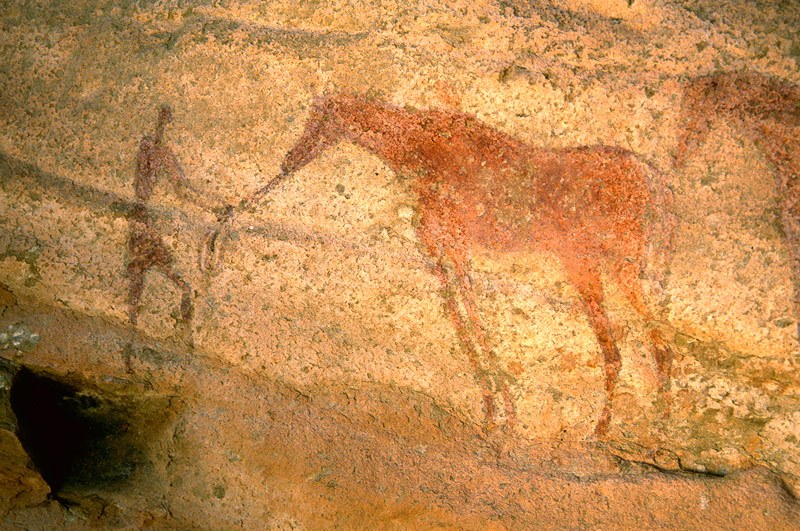 Tassili n'Ajjer, SE Algeria. Faded red standing man holding reins of faded red horse facing left. Image ID: algtdj0010016