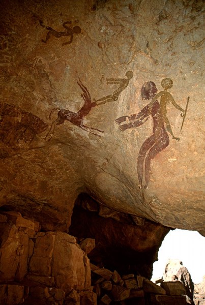 Djanet, Algeria. At right, woman with breasts and much decorated body and legs, holds stick, strides right, superimposed over person with head lowered and arms outstretched facing left. Image ID: algdja0030018