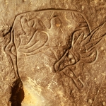 Tassili. Oued Dider, Algeria. Deeply engraved antelope, 0,47 metres, with polished lines and decoration. Extended back leg touches hole in rock that holds water after rain. Image ID: algtdi0010029