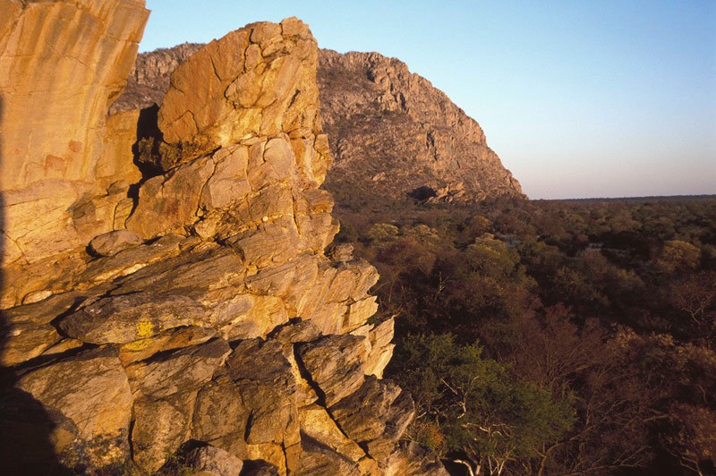 Tsodilo Hills. Exposed quartzite-schist face about 15.0 m above ground level. Finger paintings in red of eland and giraffe, and positive handprints. Male Hill, Tsodilo in background. Khoesan herder art, AD 1-1 000. Image ID: bottsd0040001