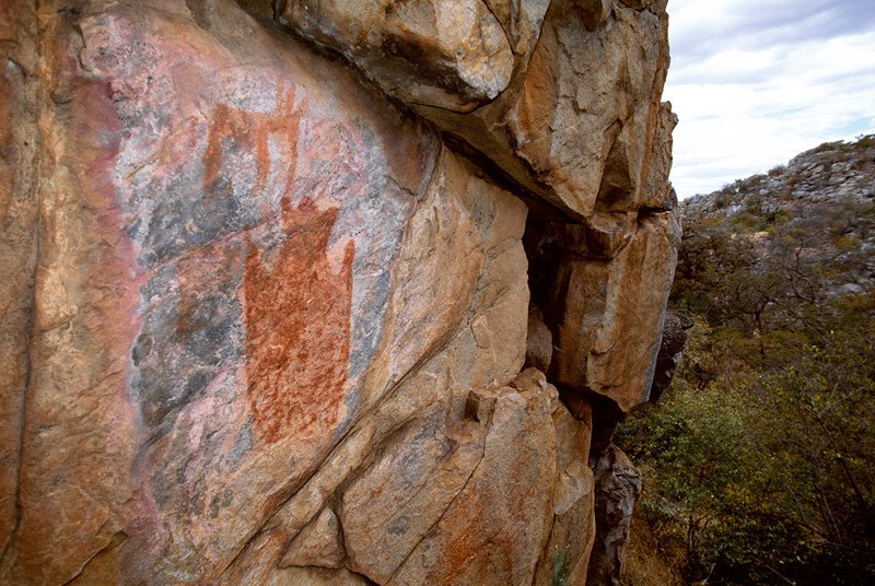 Tsodilo Hills. Top, small elephant facing right above silhouette "stretched skin" design. Bottom, very faded giraffe facing right. Image ID: bottsd0100004