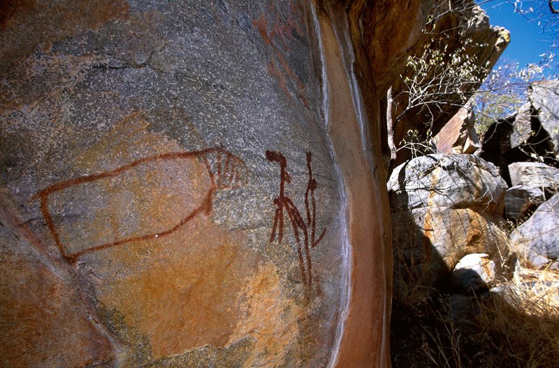 Tsodilo Hills. Schematic dancing woman facing outline hippopotamus all superimposing a giraffe facing left. Image ID: bottsd0320001