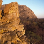 Tsodilo Hills. Exposed quartzite-schist face about 15.0 m above ground level. Finger paintings in red of eland and giraffe, and positive handprints. Male Hill, Tsodilo in background. Khoesan herder art, AD 1-1 000. Image ID: bottsd0040001