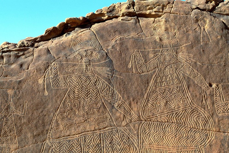 Ennedi plateau. Details of two large decorated figures. Note square hole in rock base below feet of figures. Image ID: chaenp0010030