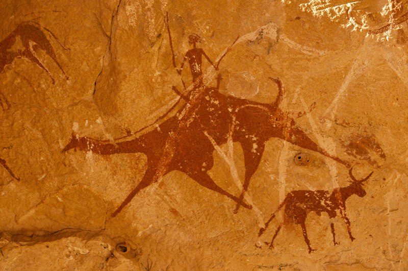 Ennedi plateau. Painting of a camel and a rider, two cows to the left and right. Image ID: chaenp0060036