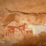 Tassili du Kozen. From left, bichrome red and white man wearing clock and headdress and holding white stick faces towards bichrome elongated cow with udder facing right, bichrome calf, and silhouette white bull facing left. Image ID: chatdk0010051