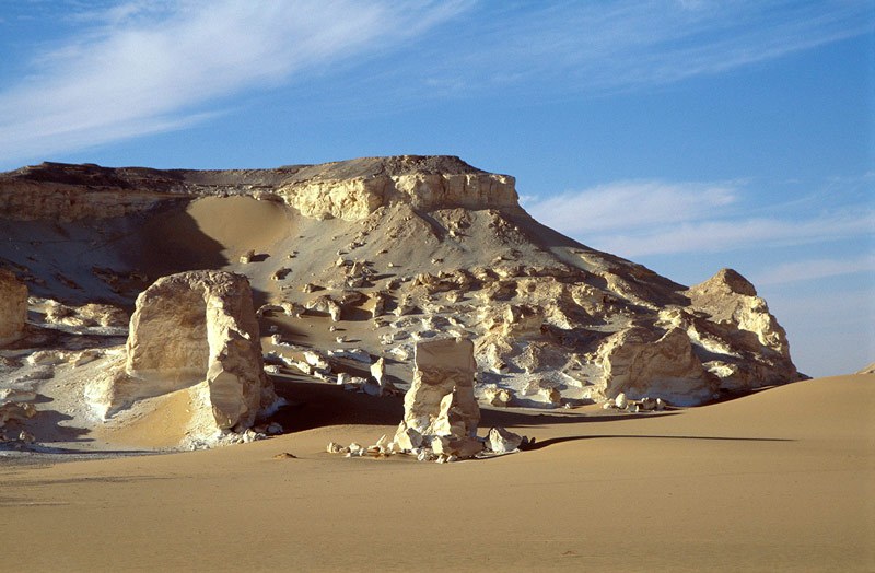 Wadi el Obeyied. Limestone outcrops and cliff. Entrance to cave site just visible at top oif sand dune close to shadow. Image ID: egyweo0010002