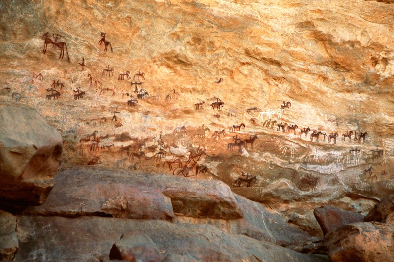 Tagant, Mauritania. Central main painted panel above ledge on cliff. From left, Four men carrying horizontal bichrome box. (horses and riders?). Image ID: mauaio0010027