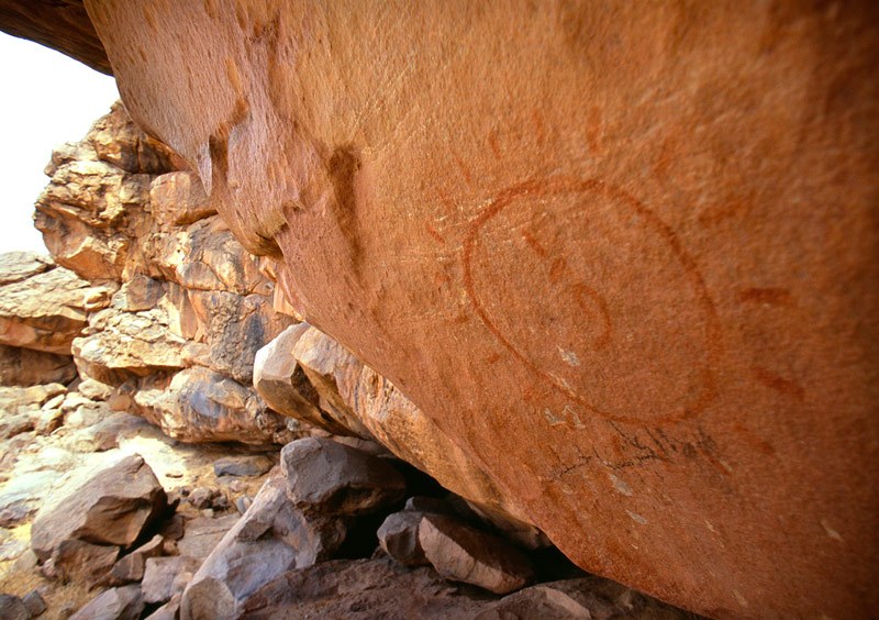 Large red mythical animal (first described as ‘dinosaur’ but probably giraffe) with two red men with arms extended mounted on horses. Image ID: mauaio0040009