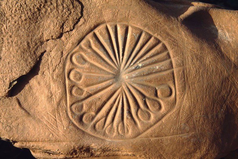Atlas Mountains, Morocco. Rock with Tazina-style engravings of spoked wheel placed in homestead courtyard wall. Image ID: moratm0010004