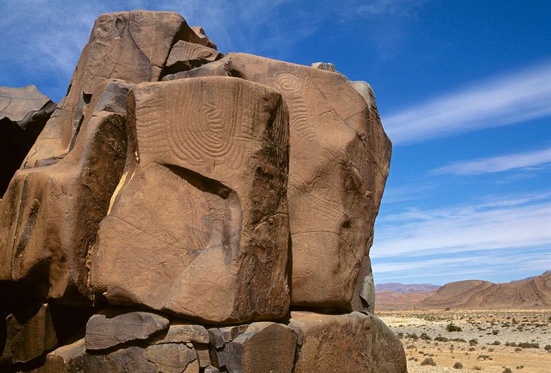 Atlas Mountains, Morocco. Curvilinear geometric designs pecked and then ground into the summit of large stepped sandstone blocks resting on sandstone bedrock. The designs incorporate vertical expanding concentric ovals flanked at either side by a design of half concentric ovals. Image ID: moratm0080004