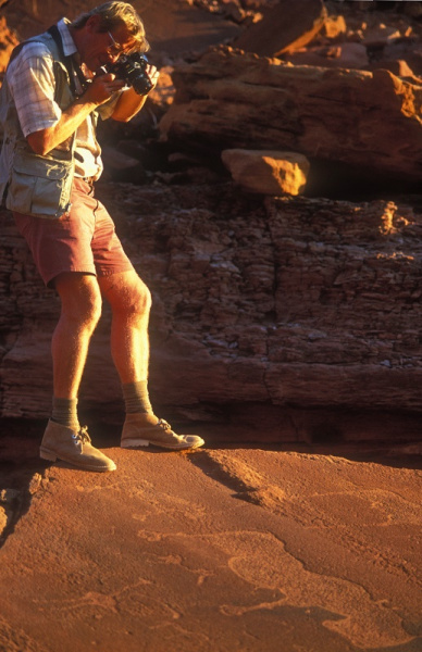 David Coulson balances on the edge of a rock to capture a panel of engravings