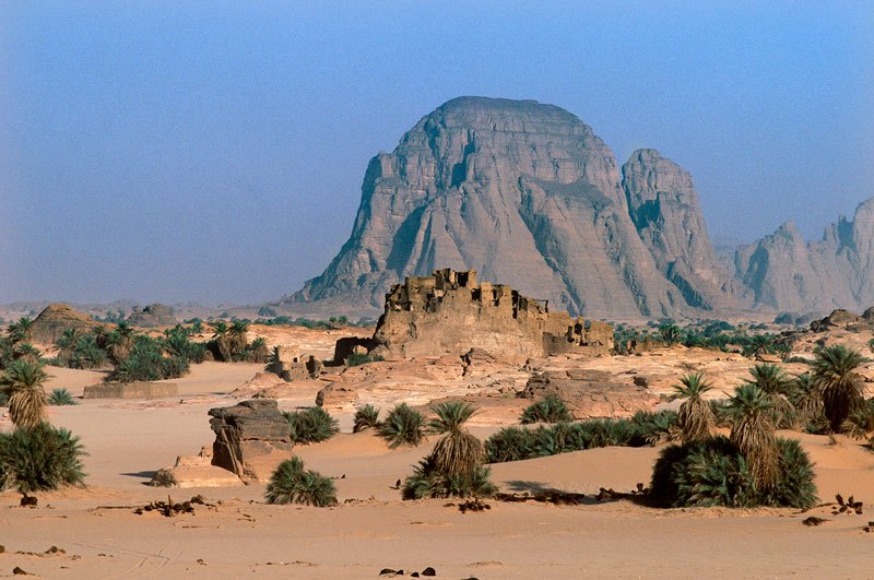 Djaba, Niger. View of town showing crumbling buildings perched on sandstone outcrop and date palms. Image ID: nigdjd0010010