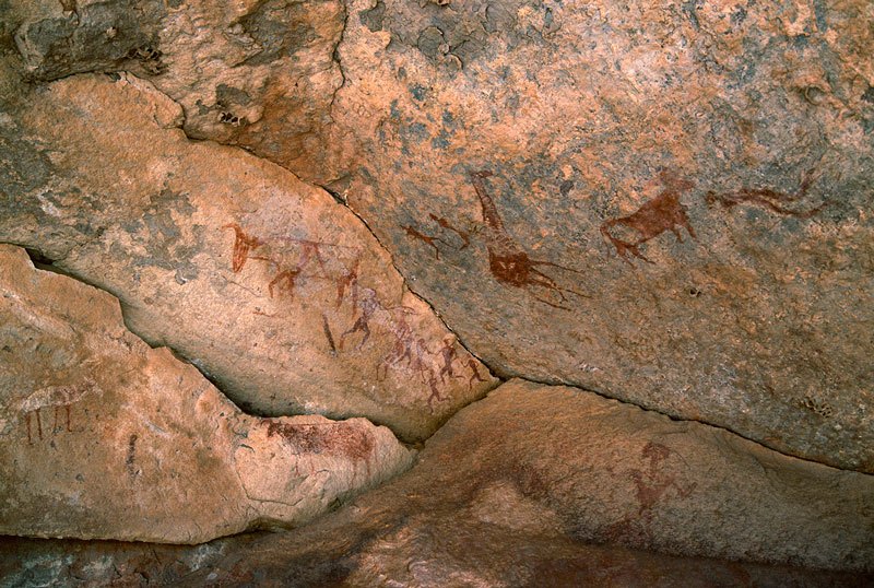 Djaba, Niger. Cow(?) facing right with white body outlined in red and red legs. Bichrome cow facing left with deliberately deformed horns. Red decorated cow facing left with deliberately deformed horns. Bichrome giraffe and two red people. Image ID: nigdjd0050010
