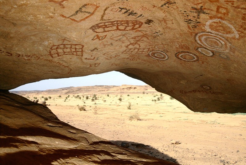 Northern Air Mountain. On roof of low but fairly deep sandstone shelter some four metres above oued, paintings in maroon, red and bichrome of geometric designs and Tifinagh script: bichrome concentric circles, circles, squares, grids and Tifinagh script. Image ID: nignam0020002