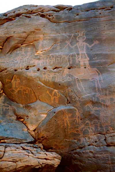Western Air Mountains, Niger. Libyan warrior wearing headdress and decorated tunic with lower edging, holds javelin in raised hand. Line of ostriches, horses and camel. Small man on horse, camels, ostrich and horse. Block-pecked antelope/cow faces left. Image ID: nigwam0050021