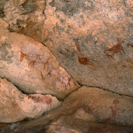 Djaba, Niger. Cow(?) facing right with white body outlined in red and red legs. Bichrome cow facing left with deliberately deformed horns. Red decorated cow facing left with deliberately deformed horns. Bichrome giraffe and two red people. Image ID: nigdjd0050010