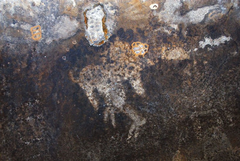 Dhayamole. White, outliner animal containing web-shape facing right (elephant?) above silhouette white antelope. Image ID: somdha0020024