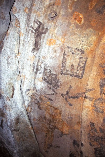 Dhayamole. Black, decorated square. Black man striding right. Faded black and orange shapes. Orange oval containing grid. Black animal (rhinoceros?) with hump. Orange shape stippled white. Image ID: somdha0020032