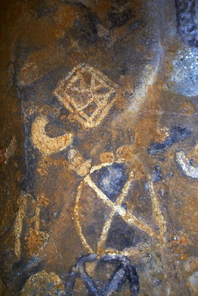 Dhayamole. Orange oval containing cross. Double square containing web. Cresent outlined in black. Faded shapes and seven white dots. Image ID: somdha0020041