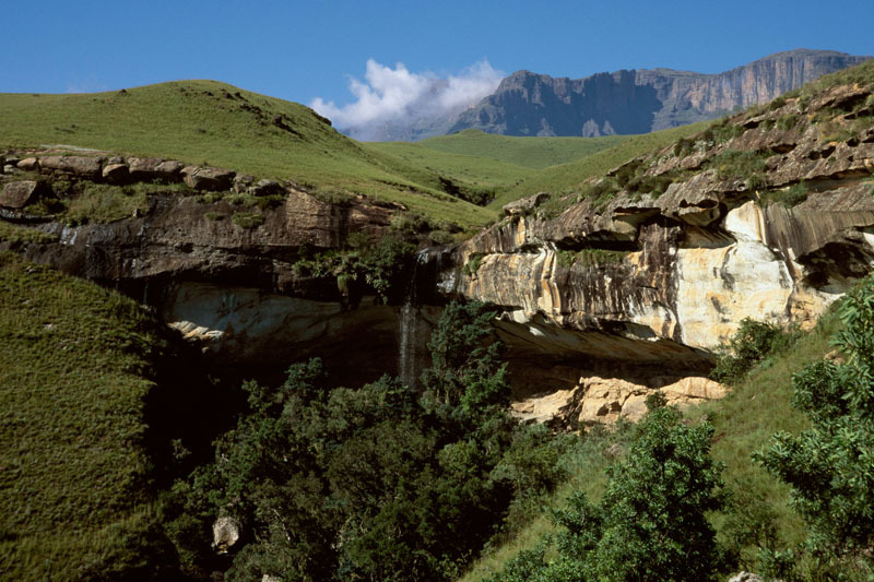 Contextual view of site previous showing the huge rock shelter with waterfall and the high peaks of the mountains behind, SOADRB0040076