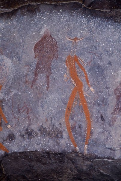 Drakensberg, South Africa. Left figure, clad in highly decorated kaross, has antelope’s head: right figure with elongated legs wears animal mask, has erect hairs on arms and legs, clouds of pink dots beside stomach, and antelope hoofs. Image ID: soadrb0080020