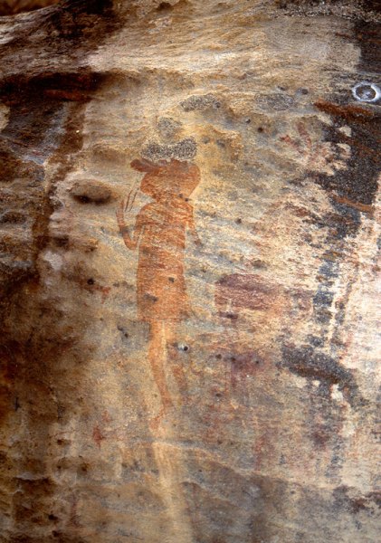 Left, red figure wearing dress and blue spotted ‘clover-leaf’ headdress has one hand raised to two lines descending from nose. Right, red animals facing right. Dark blue animal with large head (hippopotamus). Image ID: tankon0020031