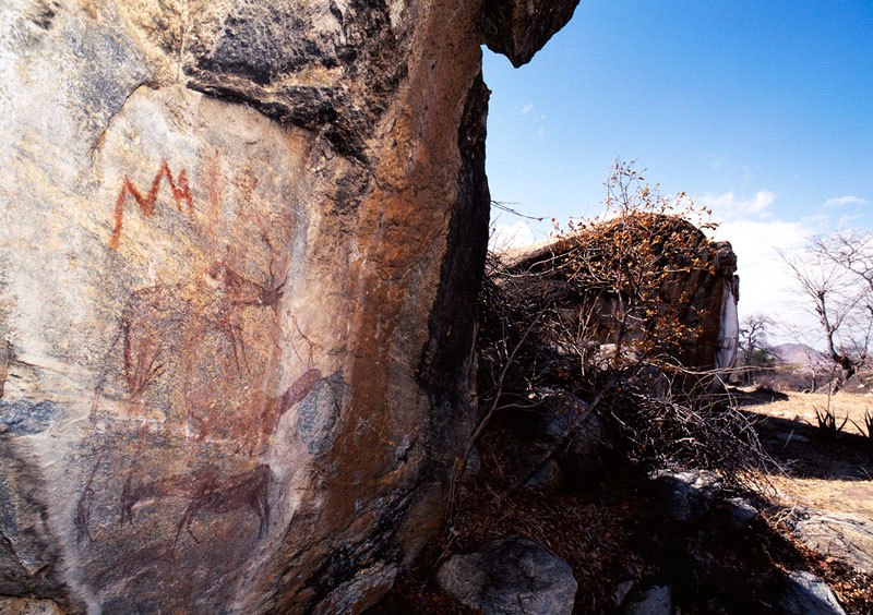 Red fine-line paintings includes a red ‘lightning’ design, kudu faced by two men with one of them holding bow and arrow, another man, running antelope and trail of porcupine tracks. Image ID: tankon0130004