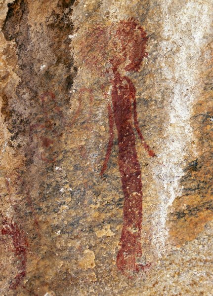 Woman wearing dress. Woman faces forwards wearing huge headdress and with arms slightly extended from sides. Image ID: tankon0160003