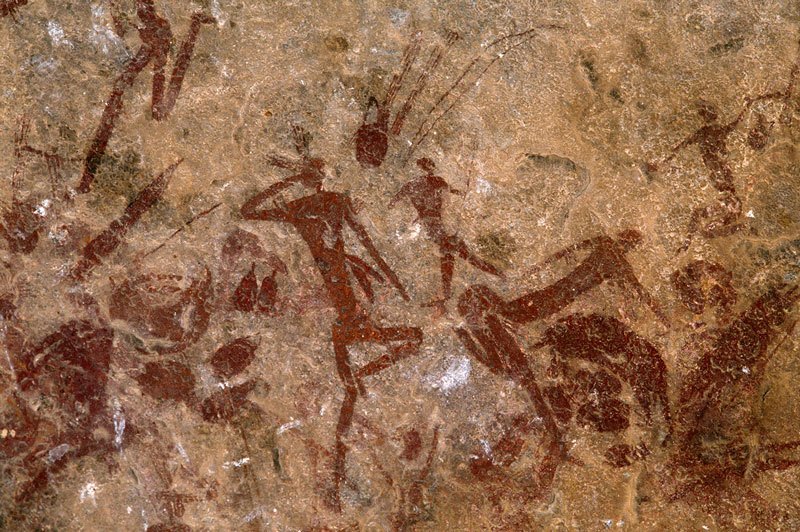 Mashonaland, Zimbabwe. Red recumbent figures amongst numerous skin bags, quivers with arrows, bow hunting bags and other equipment. Image ID: zimmsl0230043
