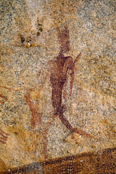Mashonaland, Zimbabwe. Man with headdress and bent legs strides left with head turned back. Feather(?) in band around left bicep. Image ID: zimmsl0260015